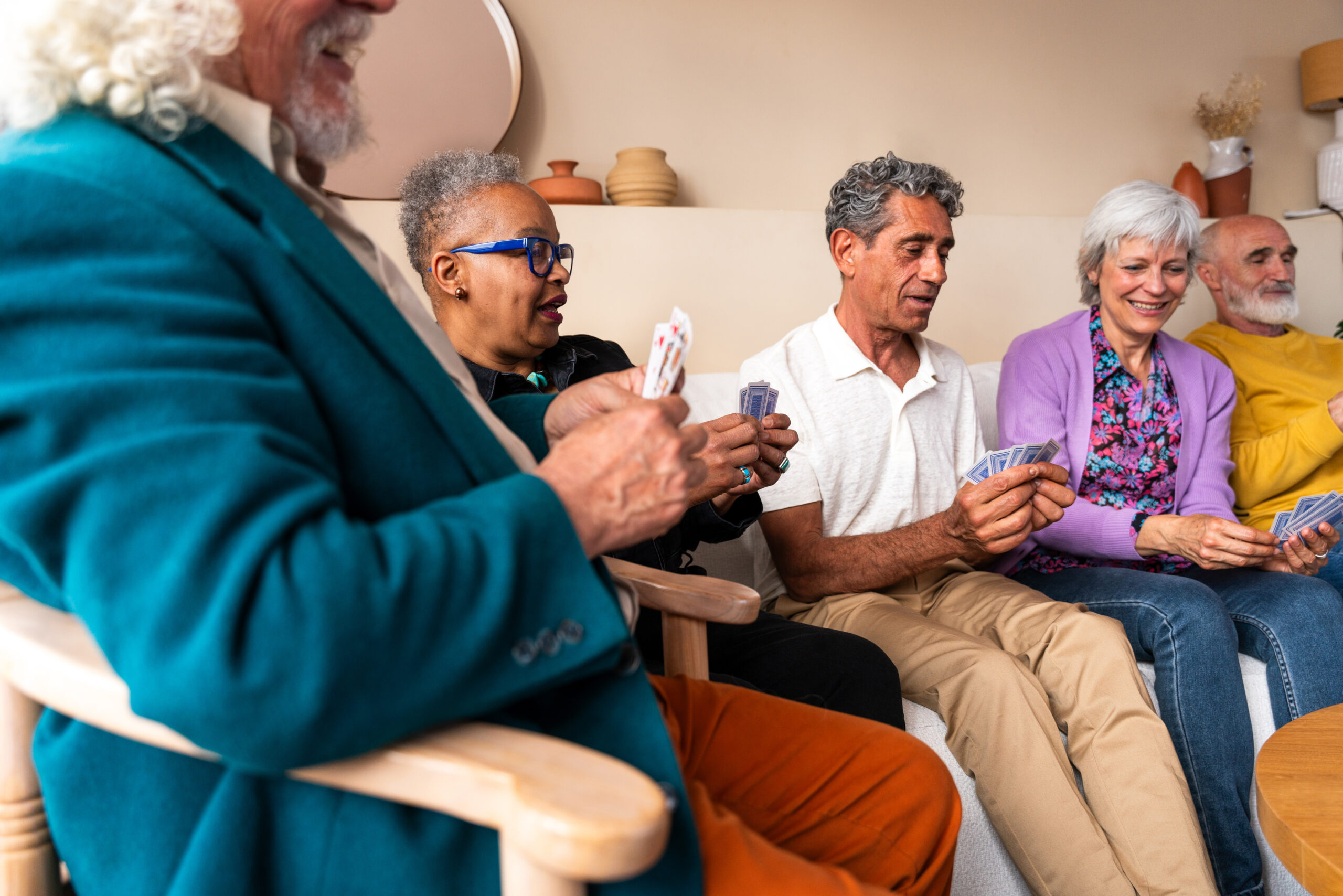 Group of happy senior friends bonding at home for dinner party - Cheerful and youthful old mature multiethnic people having fun