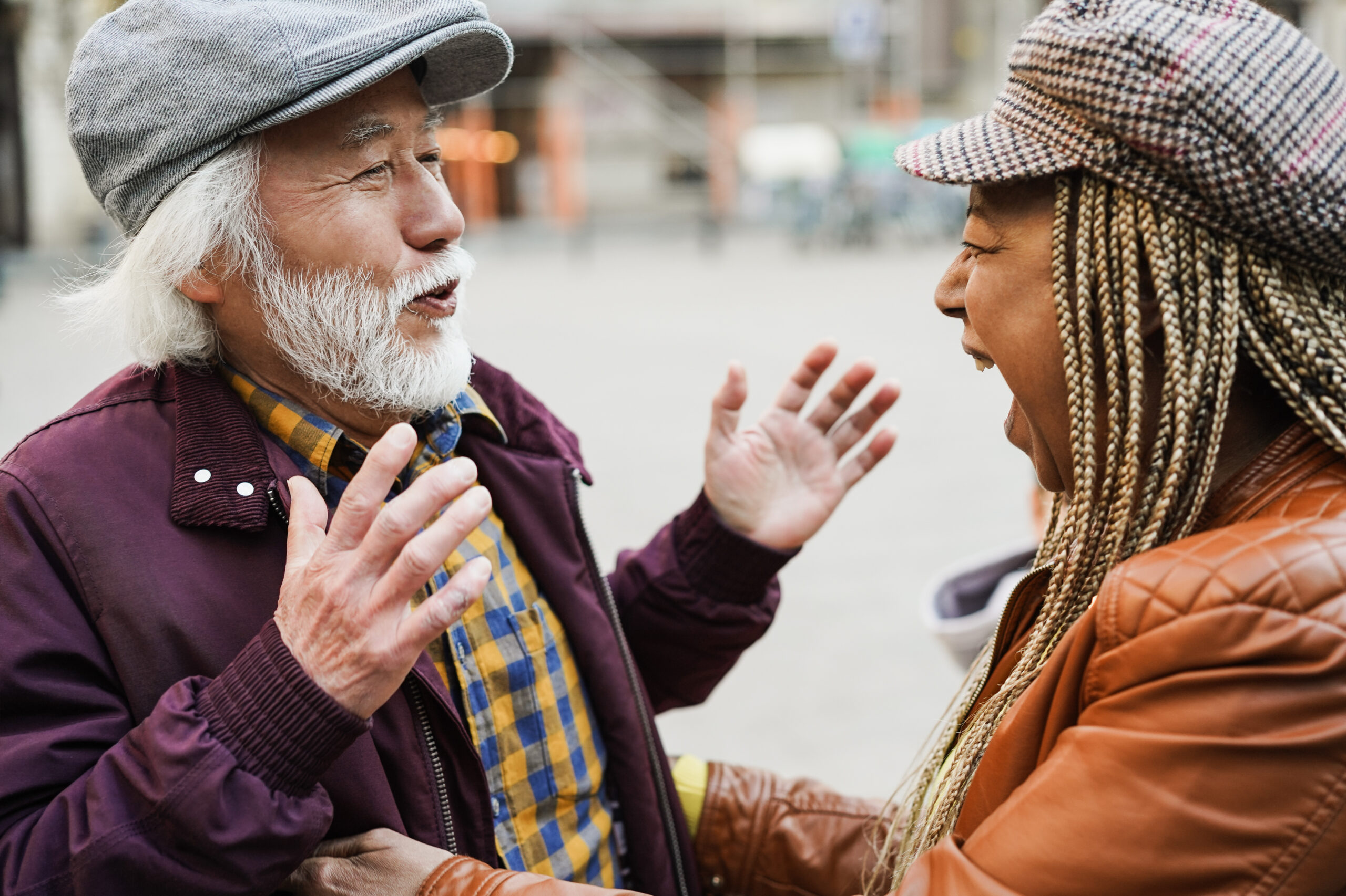 Multiracial senior friends having fun greeting each other outdoor - Soft focus on woman mouth